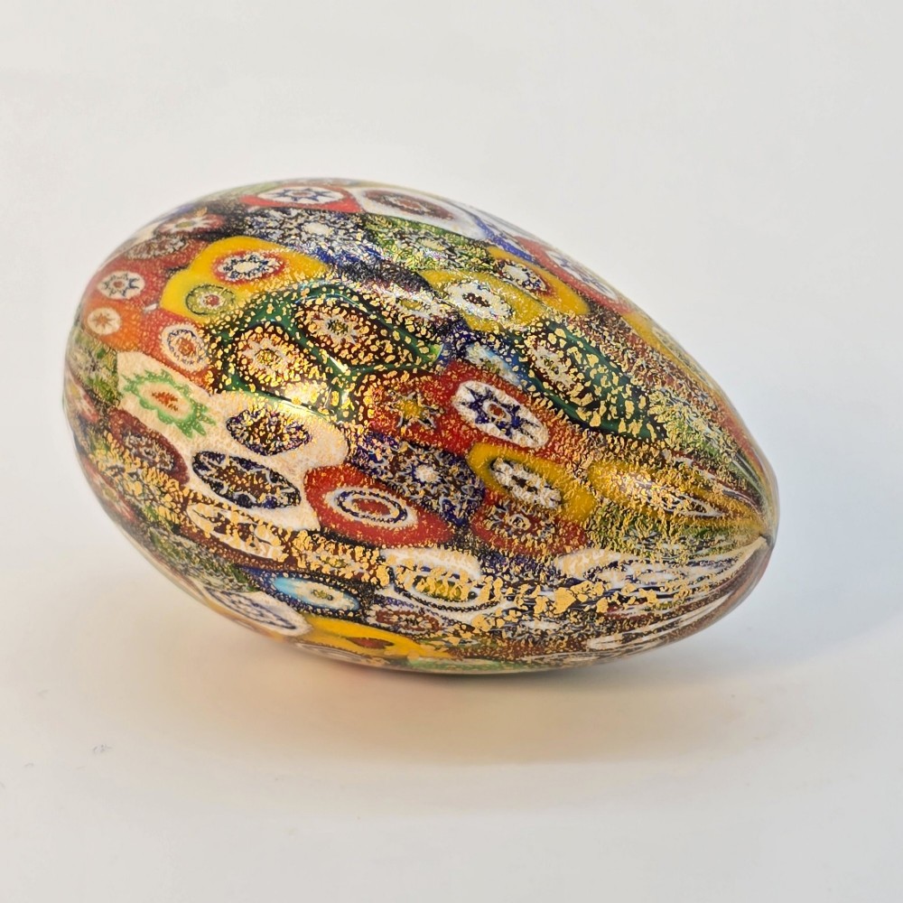 An egg-shaped Murano glass paperweight featuring colourful millefiori cane patterns and gold aventurine inclusions throughout. View V