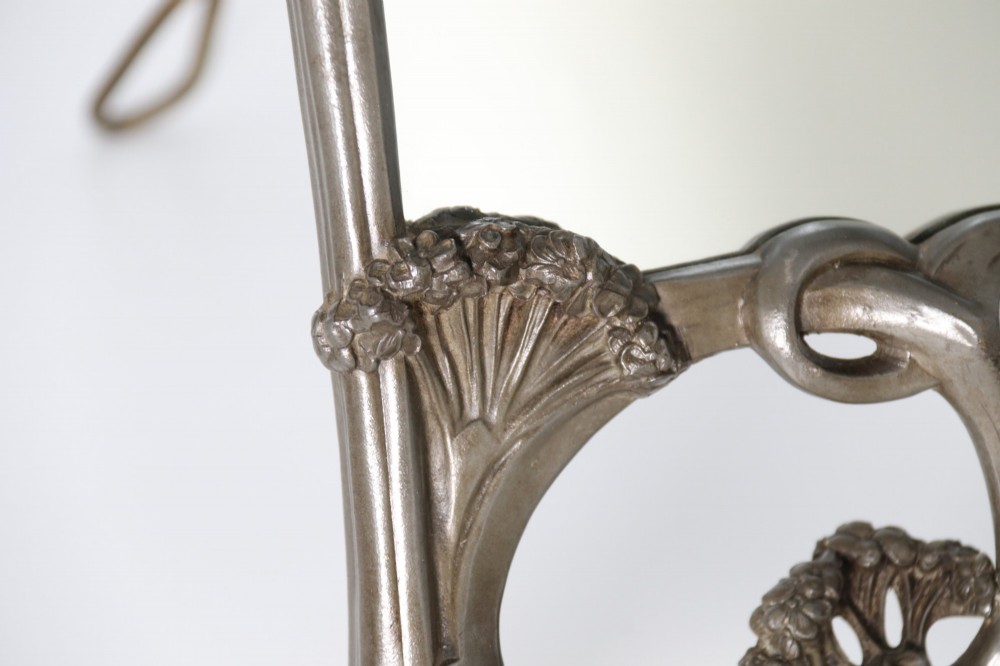 An Art Nouveau pewter table mirror featuring an asymmetrical botanical frame with organic crests and an easel back support. View IV