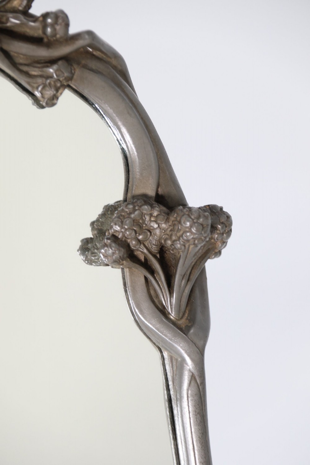 An Art Nouveau pewter table mirror featuring an asymmetrical botanical frame with organic crests and an easel back support. View V
