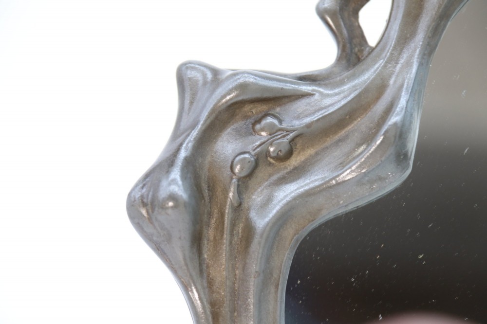 An Art Nouveau pewter table mirror featuring an asymmetrical botanical frame with organic crests and an easel back support. View VIII