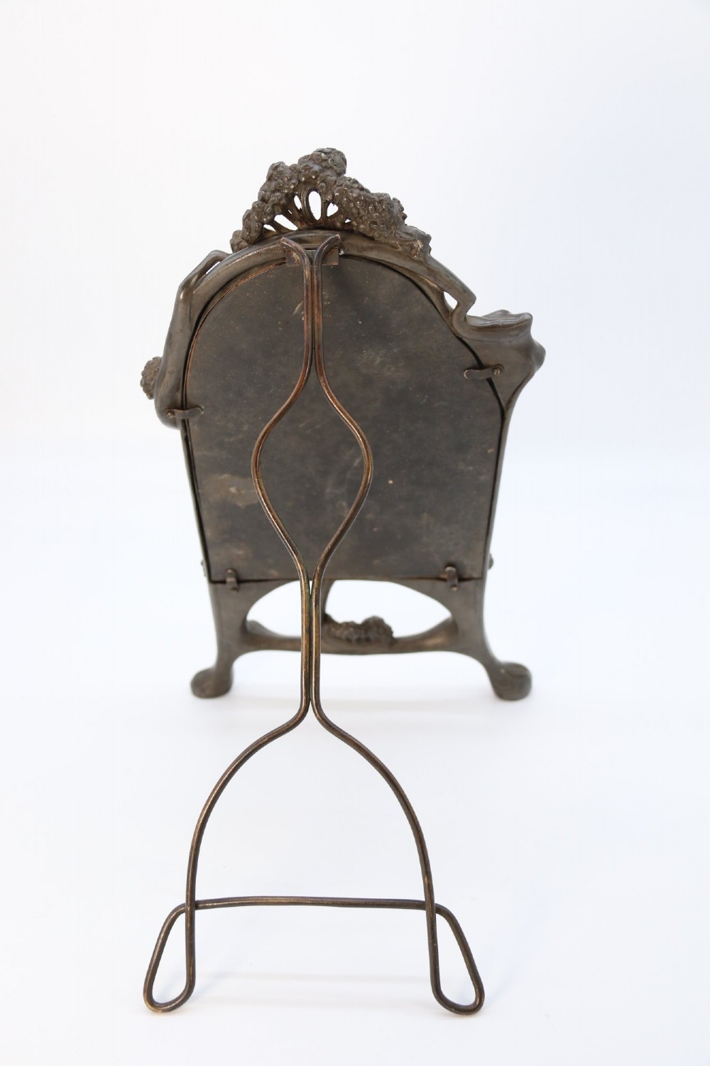An Art Nouveau pewter table mirror featuring an asymmetrical botanical frame with organic crests and an easel back support. View IX