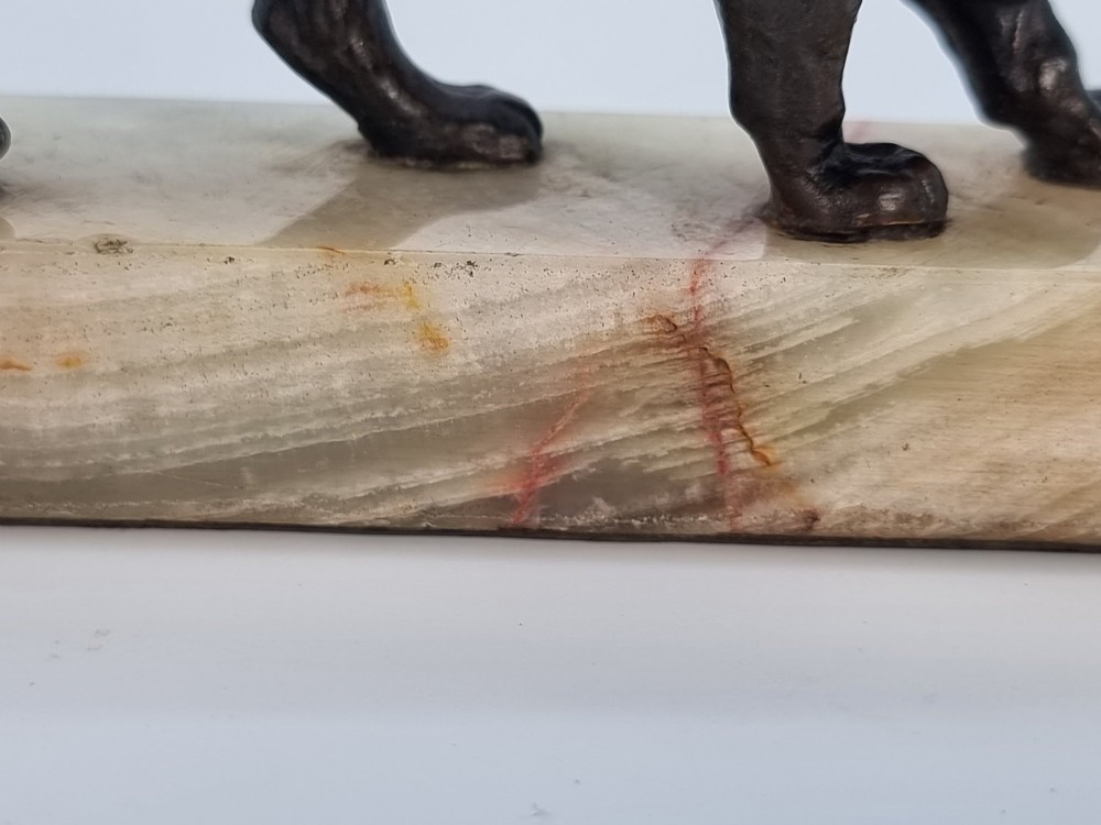 A dark patinated bronze sculpture of a prowling lion mounted on a rectangular cream veined onyx base. View X