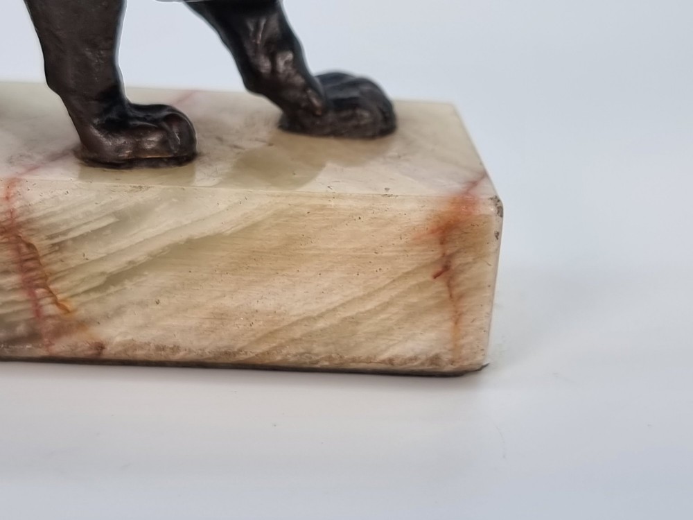 A dark patinated bronze sculpture of a prowling lion mounted on a rectangular cream veined onyx base. View XI