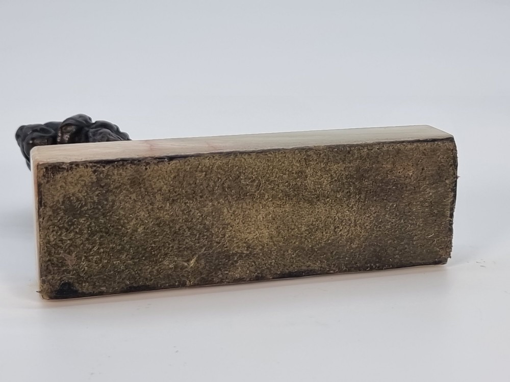 A dark patinated bronze sculpture of a prowling lion mounted on a rectangular cream veined onyx base. View XIV