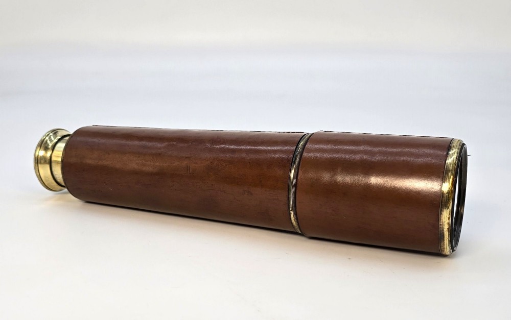 A brass multi-draw military telescope featuring stitched brown leather protective sleeves along the barrel. View II