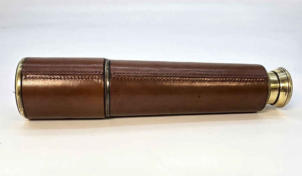 A brass multi-draw military telescope featuring stitched brown leather protective sleeves along the barrel. View IV