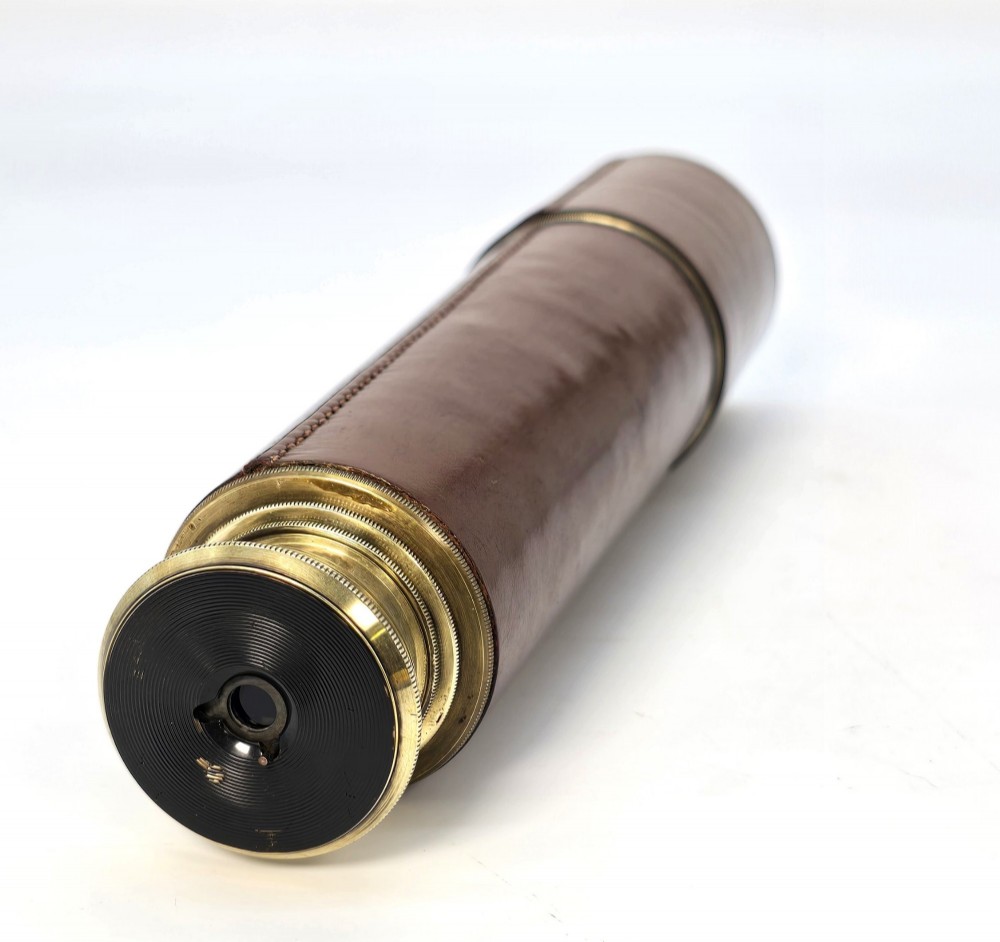 A brass multi-draw military telescope featuring stitched brown leather protective sleeves along the barrel. View V