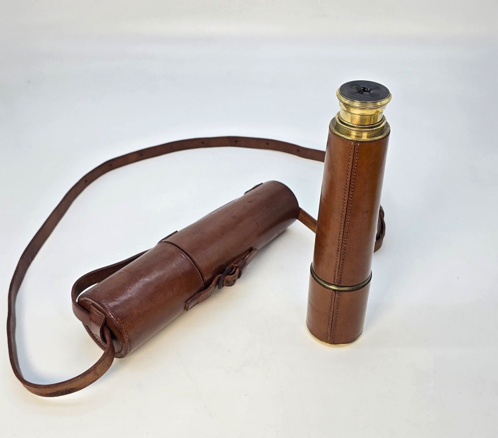 A brass multi-draw military telescope featuring stitched brown leather protective sleeves along the barrel. View VII