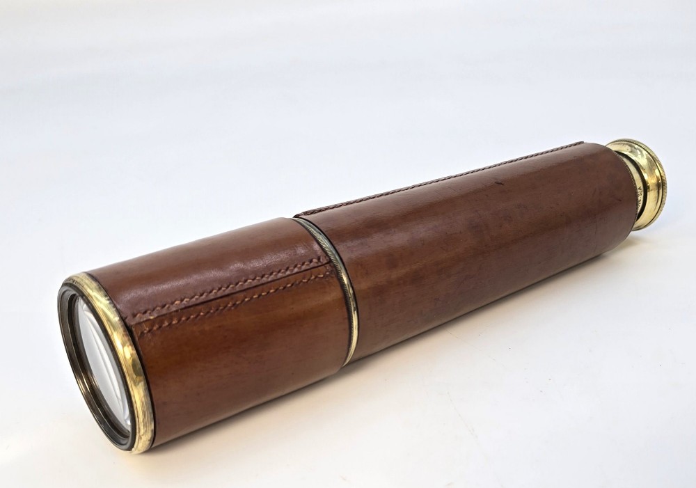 A brass multi-draw military telescope featuring stitched brown leather protective sleeves along the barrel. View XI