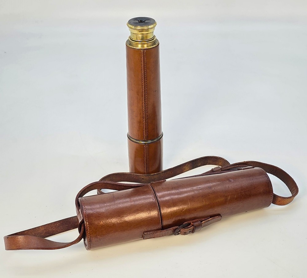A brass multi-draw military telescope featuring stitched brown leather protective sleeves along the barrel. View XII