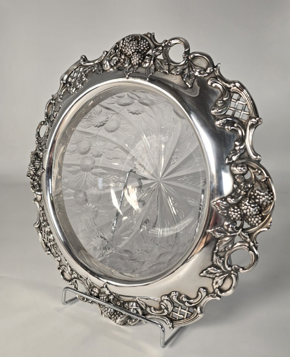 A clear crystal bowl featuring an intricately chased sterling silver rim decorated with floral motifs, scrolls, and lattice patterns. View III