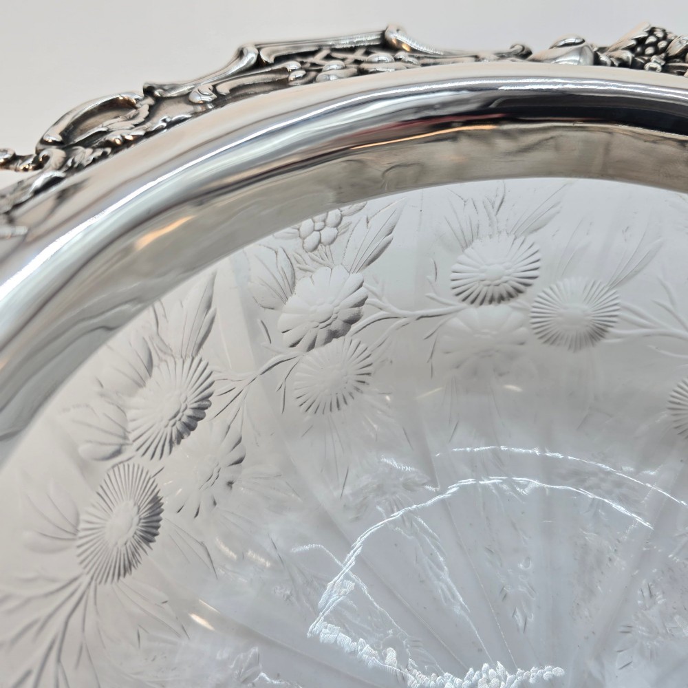 A clear crystal bowl featuring an intricately chased sterling silver rim decorated with floral motifs, scrolls, and lattice patterns. View V