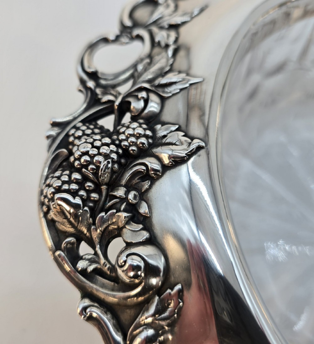 A clear crystal bowl featuring an intricately chased sterling silver rim decorated with floral motifs, scrolls, and lattice patterns. View VIII