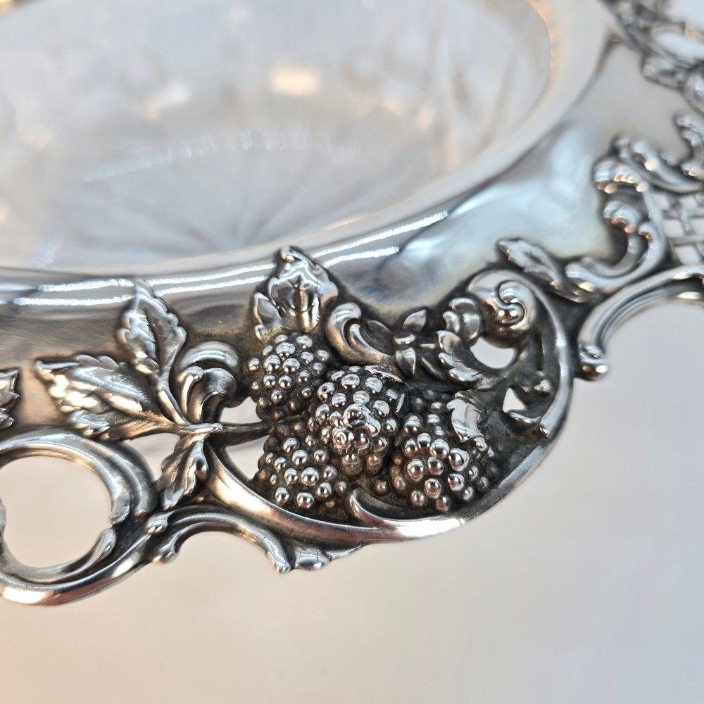 A clear crystal bowl featuring an intricately chased sterling silver rim decorated with floral motifs, scrolls, and lattice patterns. View XI