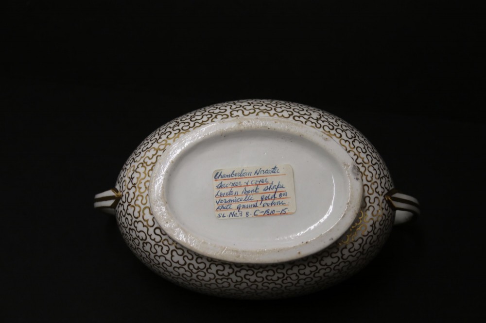 An antique white porcelain covered sucrier decorated with intricate gold scroll patterning, geometric trim, twin loop handles, and a pointed finial lid. View VIII