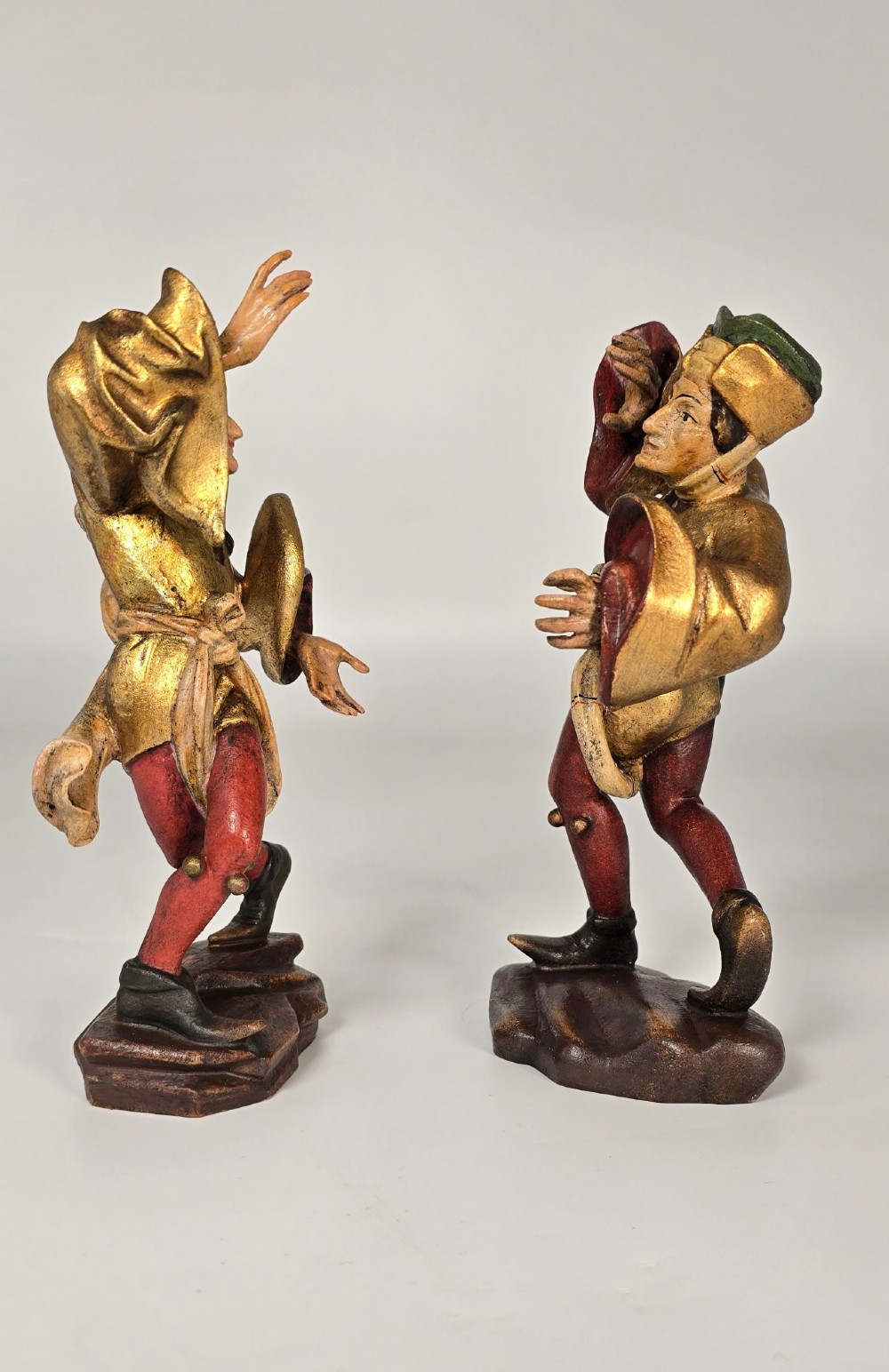 A pair of hand-carved and painted limewood figures depicting medieval dancers in gilded tunics and red hosen on carved wooden bases. View II