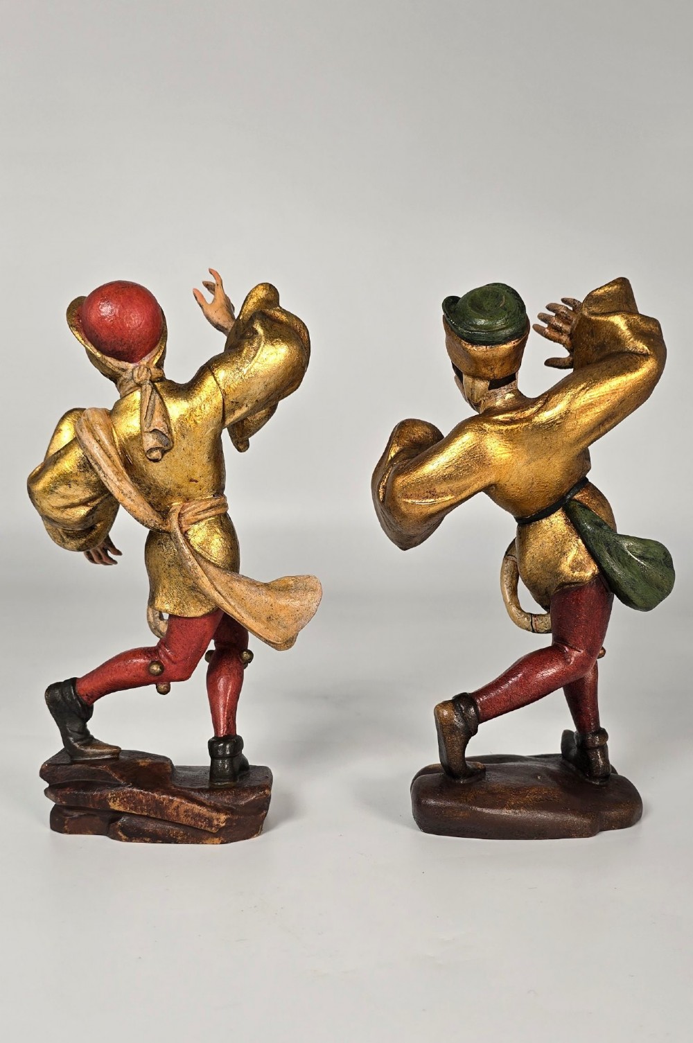 A pair of hand-carved and painted limewood figures depicting medieval dancers in gilded tunics and red hosen on carved wooden bases. View III