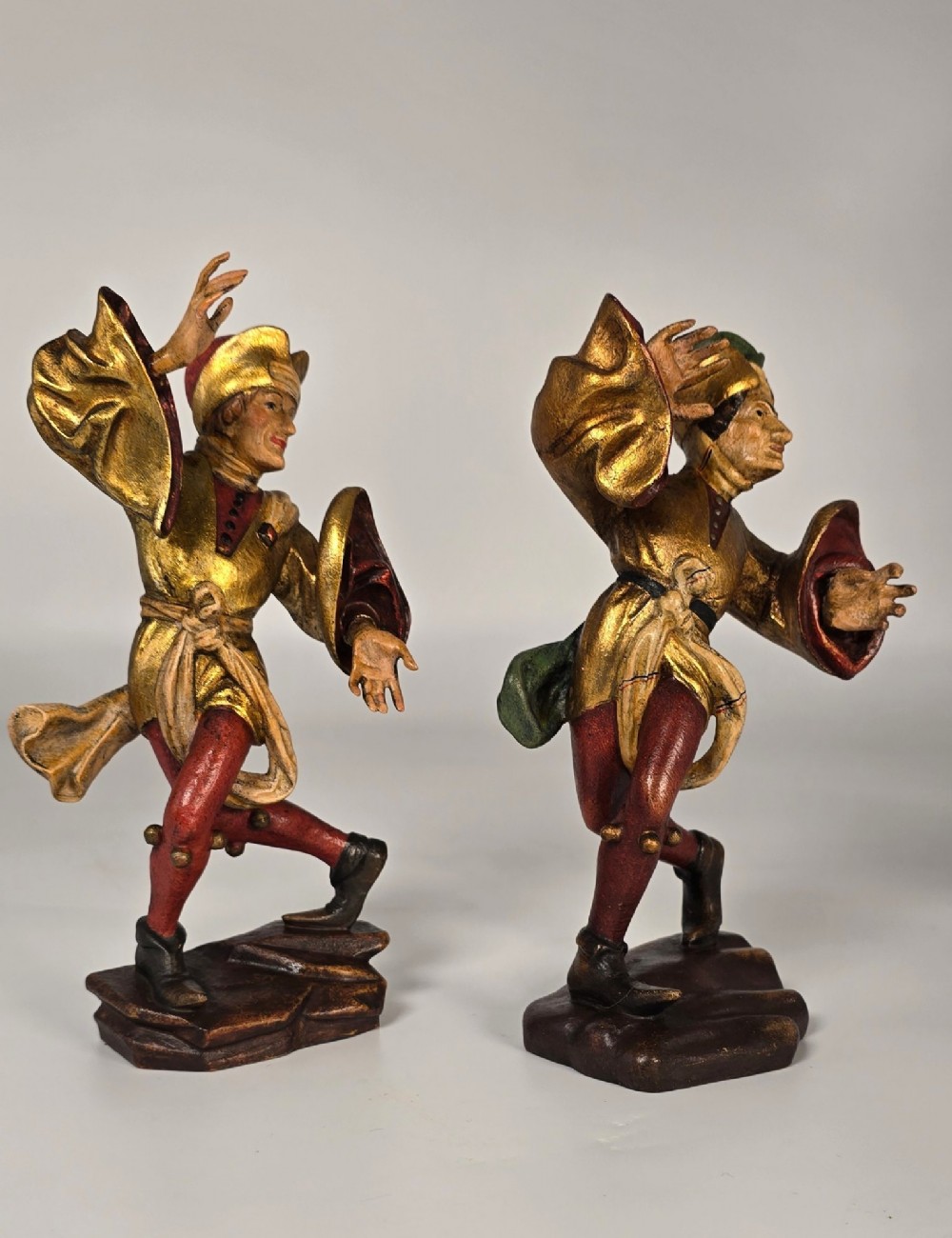 A pair of hand-carved and painted limewood figures depicting medieval dancers in gilded tunics and red hosen on carved wooden bases. View VII
