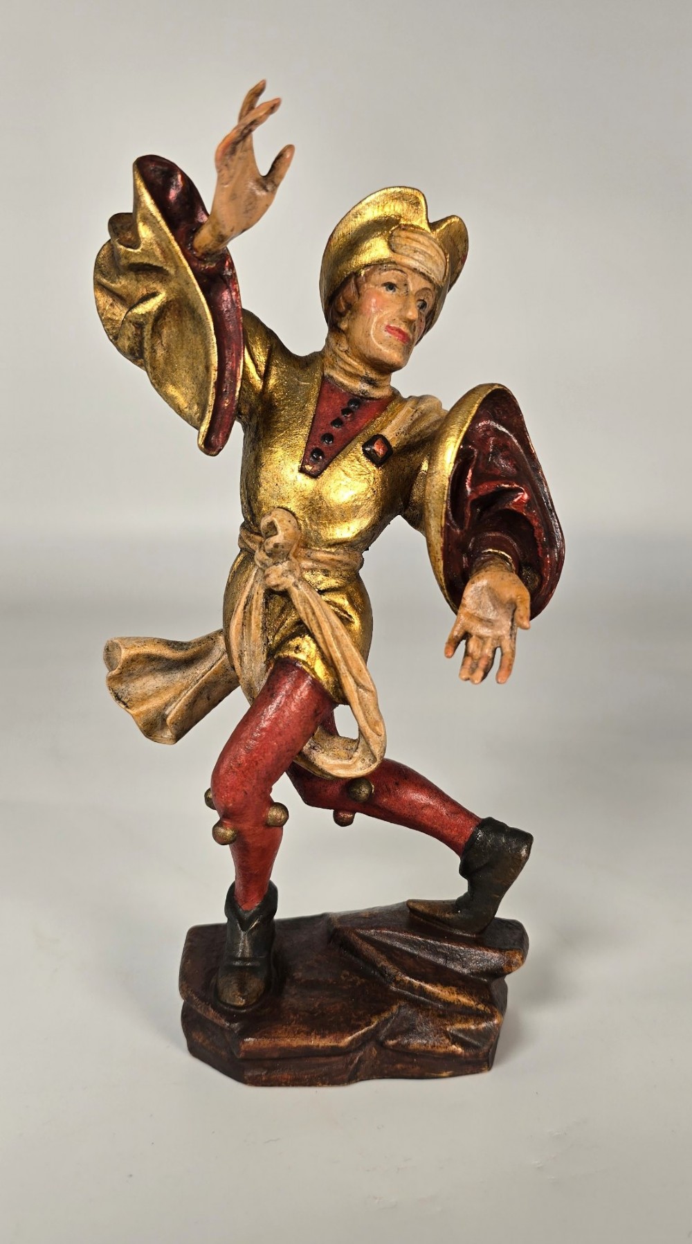 A pair of hand-carved and painted limewood figures depicting medieval dancers in gilded tunics and red hosen on carved wooden bases. View VIII