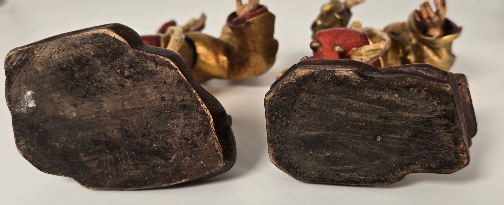 A pair of hand-carved and painted limewood figures depicting medieval dancers in gilded tunics and red hosen on carved wooden bases. View X