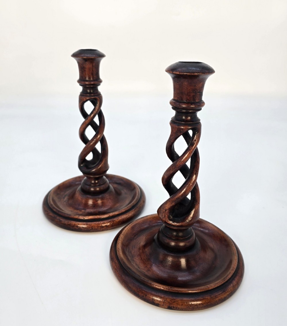 A pair of 18th-century carved fruitwood candlesticks featuring open twist stems and wide circular bases. View II