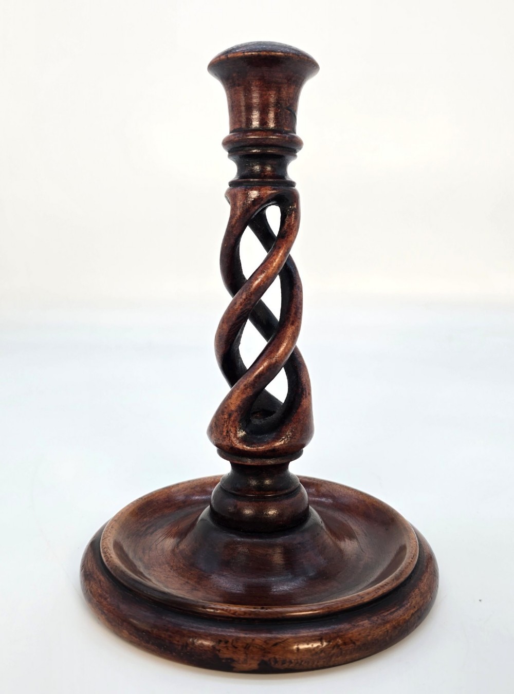 A pair of 18th-century carved fruitwood candlesticks featuring open twist stems and wide circular bases. View III