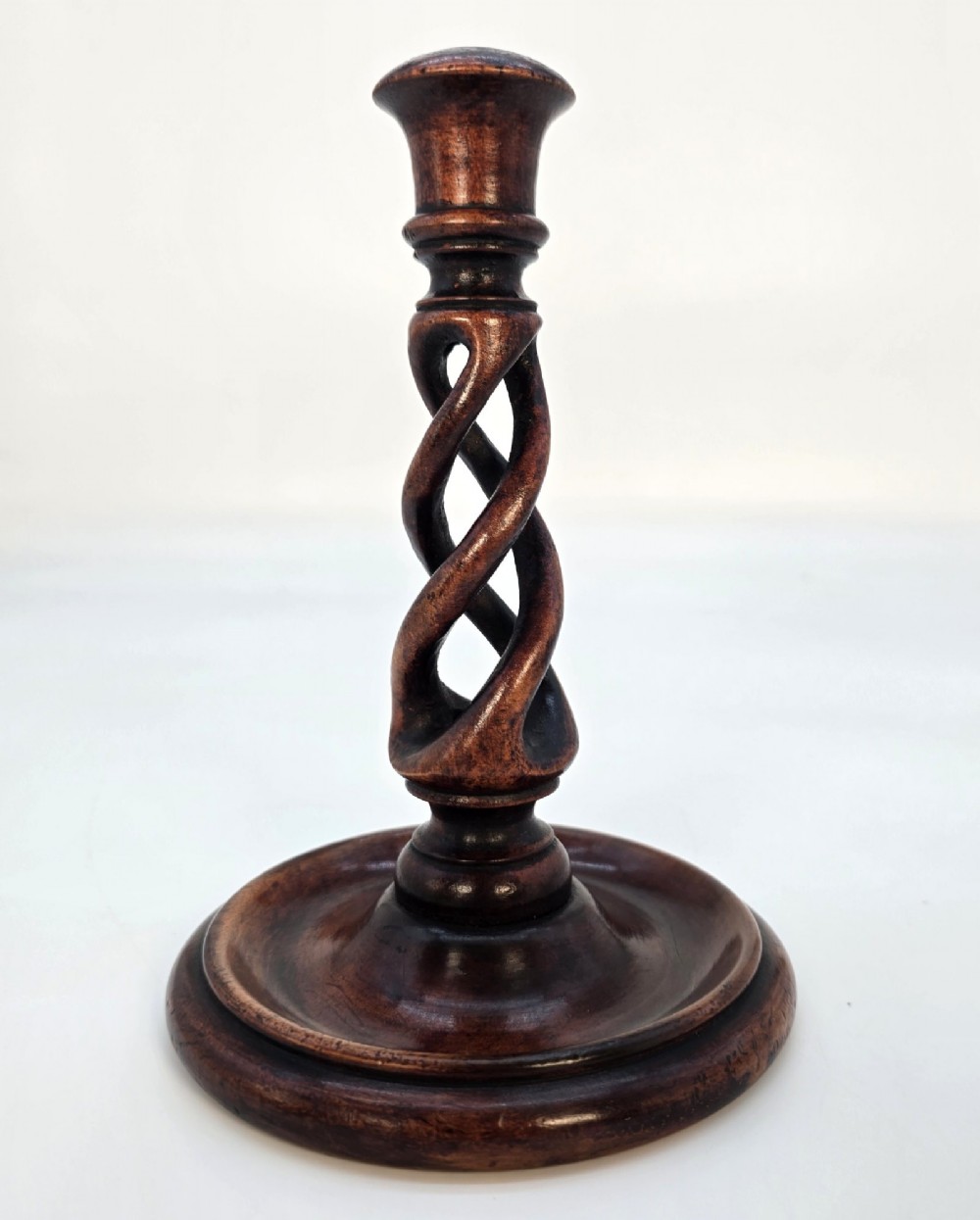 A pair of 18th-century carved fruitwood candlesticks featuring open twist stems and wide circular bases. View IV