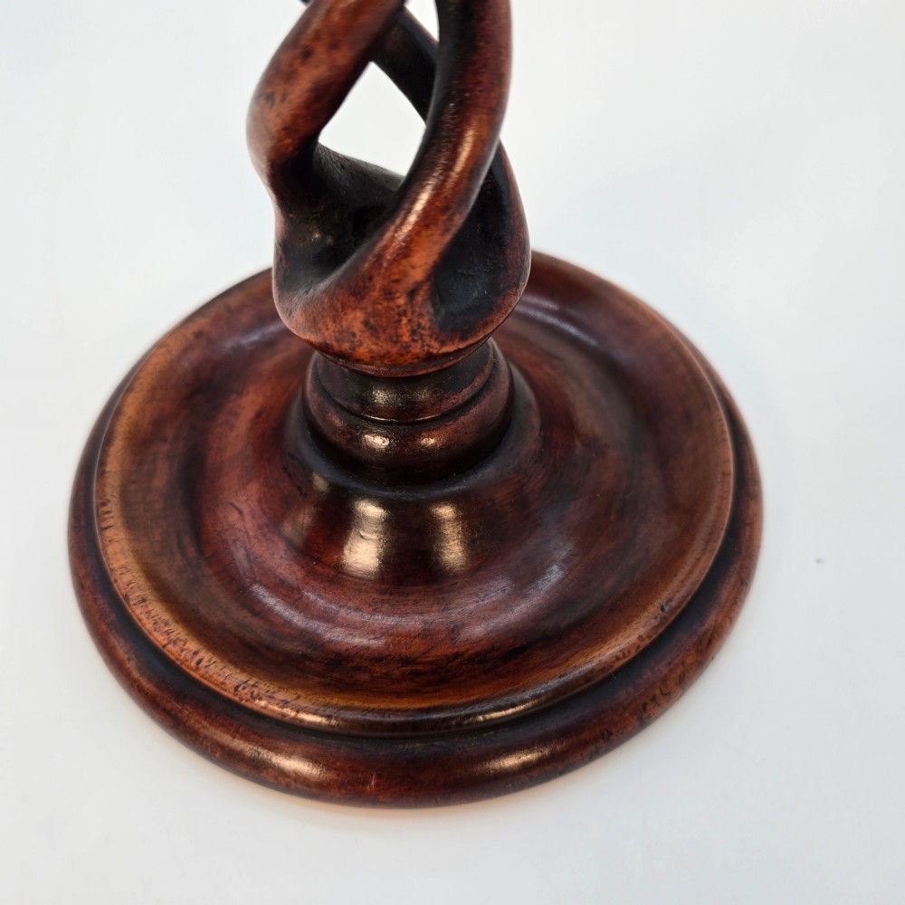 A pair of 18th-century carved fruitwood candlesticks featuring open twist stems and wide circular bases. View V