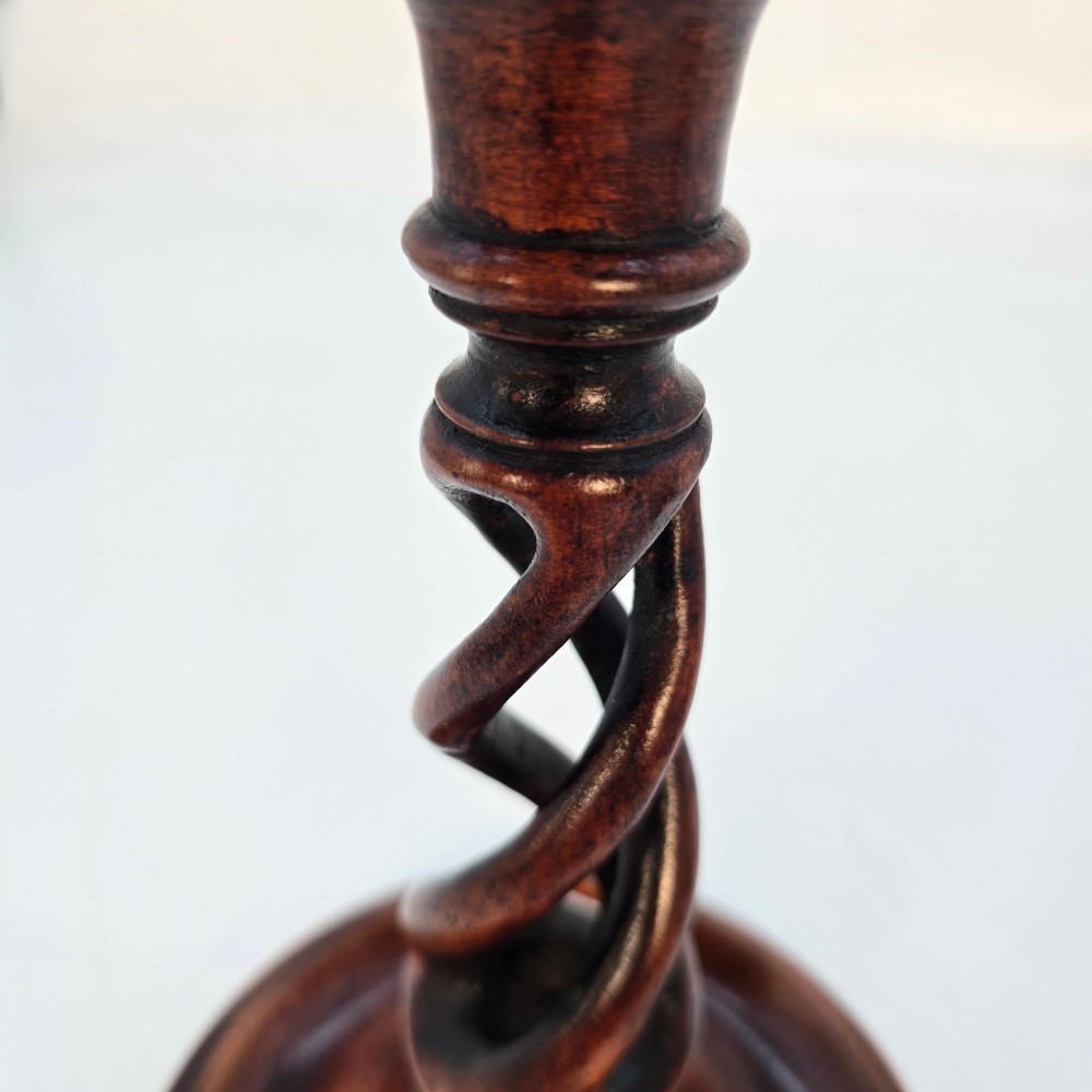 A pair of 18th-century carved fruitwood candlesticks featuring open twist stems and wide circular bases. View VI