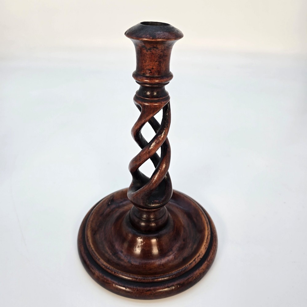 A pair of 18th-century carved fruitwood candlesticks featuring open twist stems and wide circular bases. View IX