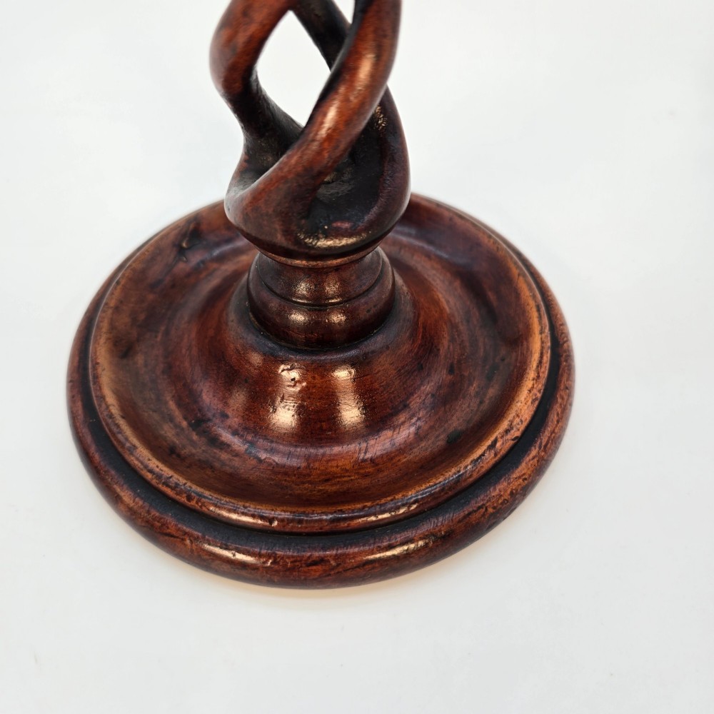 A pair of 18th-century carved fruitwood candlesticks featuring open twist stems and wide circular bases. View X
