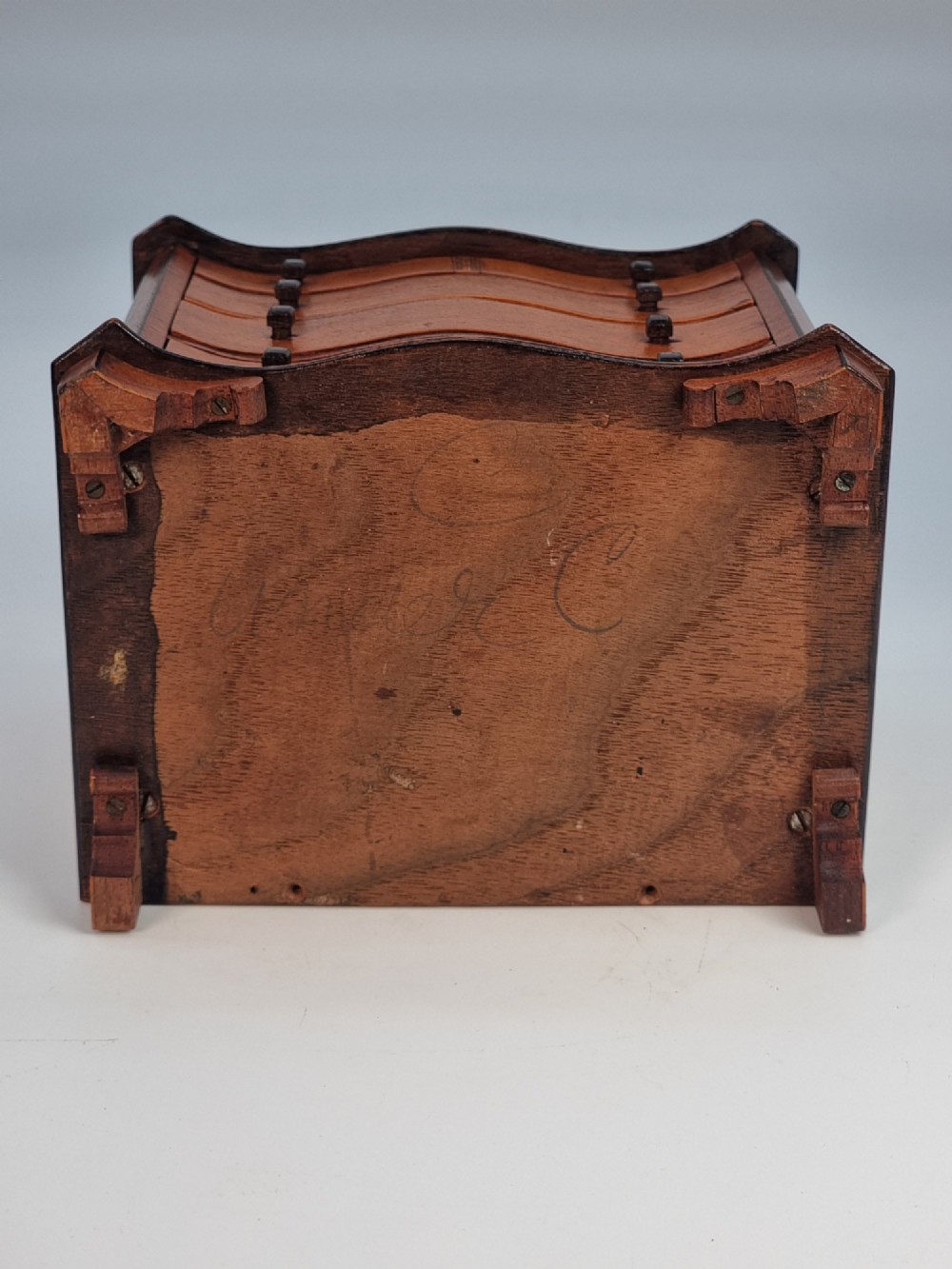 An Edwardian miniature satinwood chest of drawers featuring a serpentine front, inlaid shell medallion on the top, and four small drawers with wooden knobs. View XV