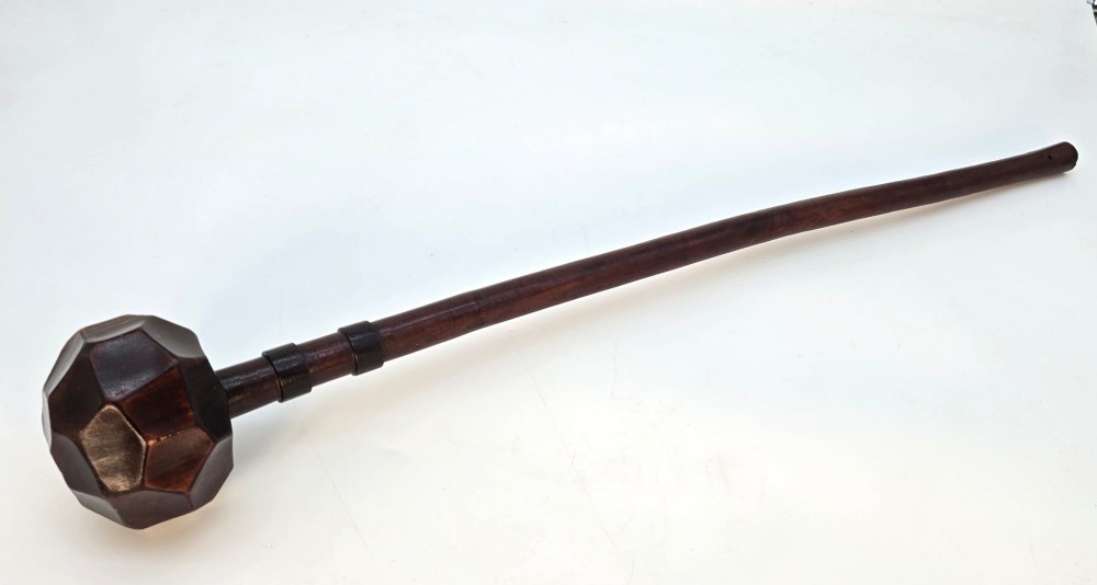 An antique dark hardwood Zulu knobkerrie club featuring a faceted spherical head and a slender shaft with raised carved rings near the top.