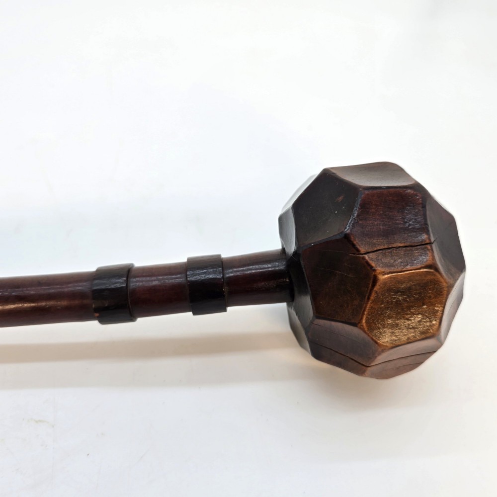 An antique dark hardwood Zulu knobkerrie club featuring a faceted spherical head and a slender shaft with raised carved rings near the top. View IV