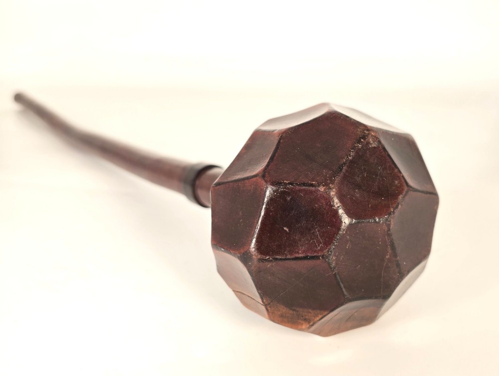 An antique dark hardwood Zulu knobkerrie club featuring a faceted spherical head and a slender shaft with raised carved rings near the top. View VII