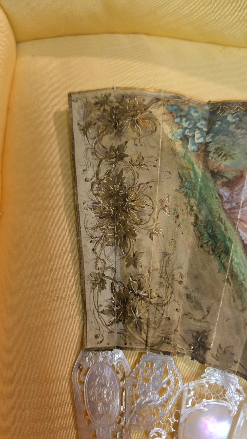 A late 18th-century Italian folding fan featuring a hand-painted pastoral scene mounted on carved mother-of-pearl sticks, presented inside a fan-shaped black frame with a cream silk lining. View IX