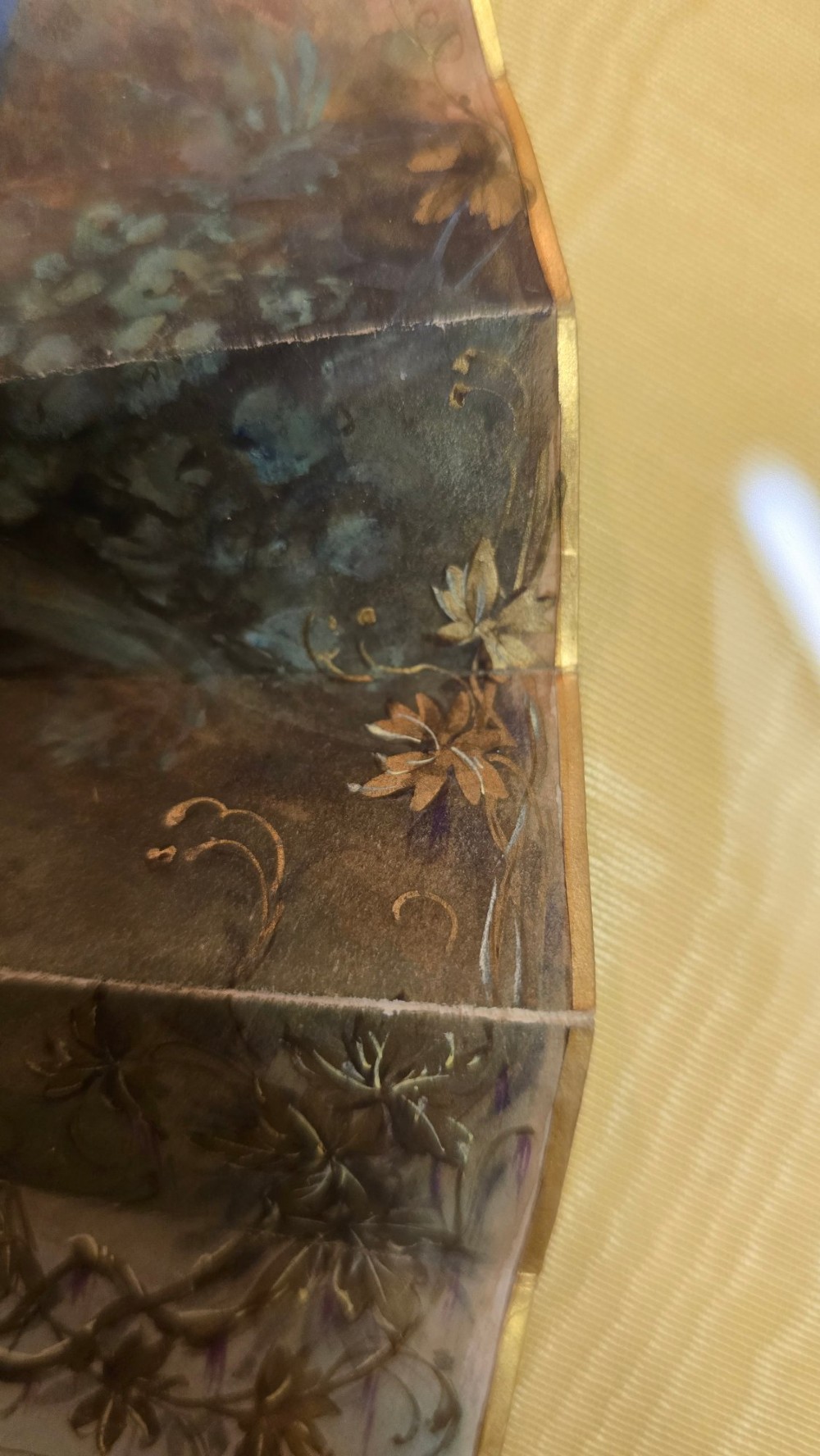 A late 18th-century Italian folding fan featuring a hand-painted pastoral scene mounted on carved mother-of-pearl sticks, presented inside a fan-shaped black frame with a cream silk lining. View XI