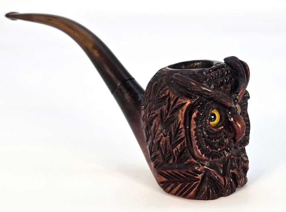 A detailed hand-carved briar wood tobacco pipe crafted in the shape of an owls head featuring yellow glass eyes and a curved black stem. View II