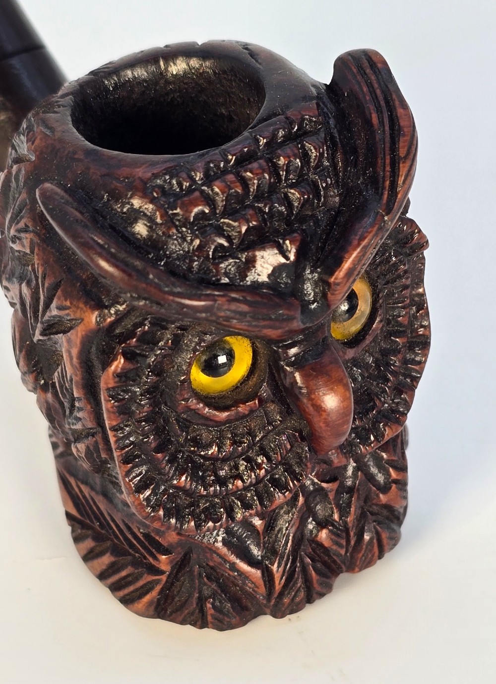 A detailed hand-carved briar wood tobacco pipe crafted in the shape of an owls head featuring yellow glass eyes and a curved black stem. View VIII