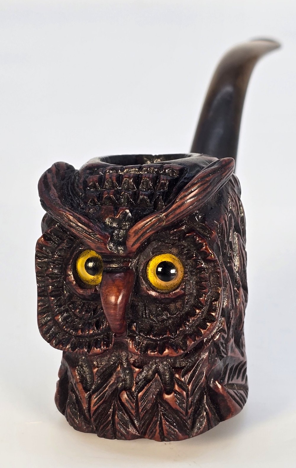 A detailed hand-carved briar wood tobacco pipe crafted in the shape of an owls head featuring yellow glass eyes and a curved black stem. View IX