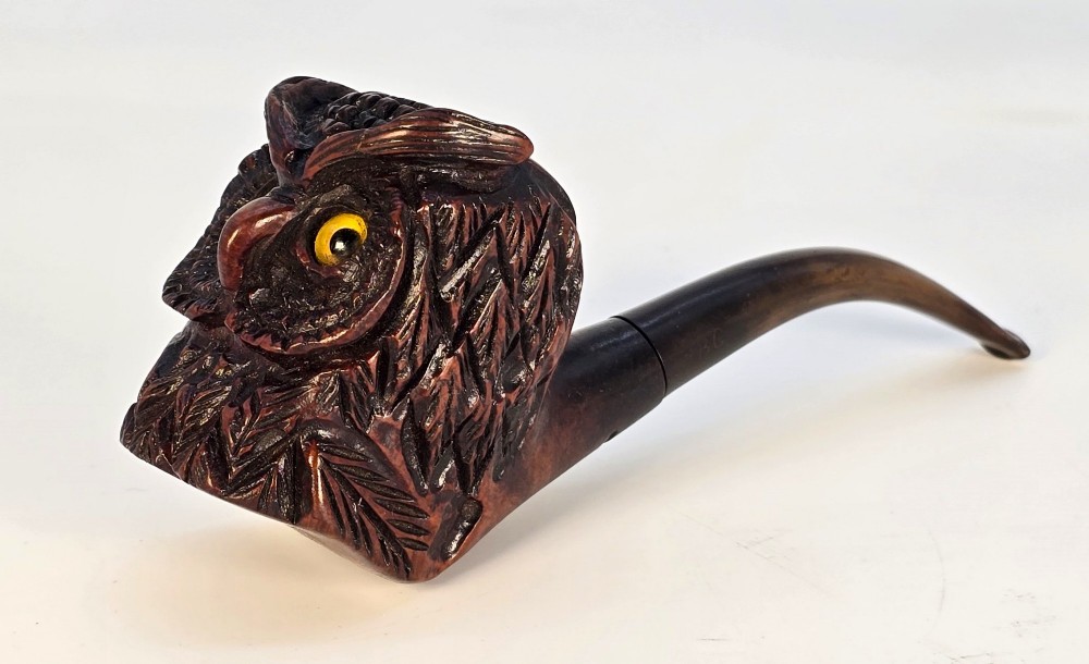 A detailed hand-carved briar wood tobacco pipe crafted in the shape of an owls head featuring yellow glass eyes and a curved black stem. View XI