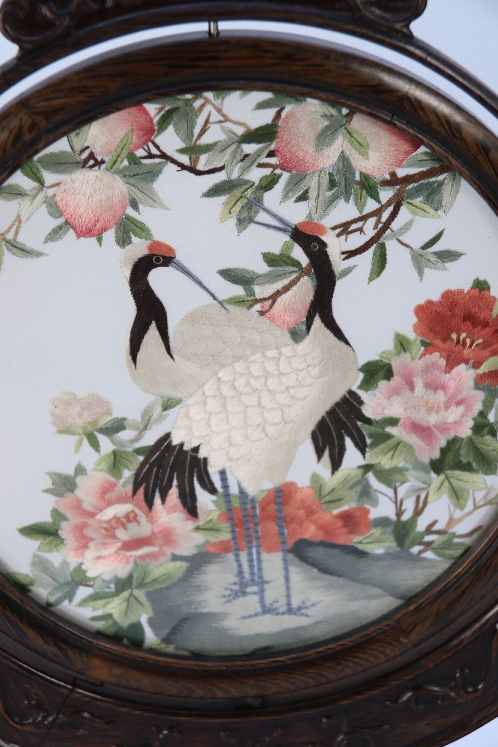 A circular double-sided silk embroidery depicting cranes among pink flowers, set within a rotating carved dark hardwood frame and stand. View VI