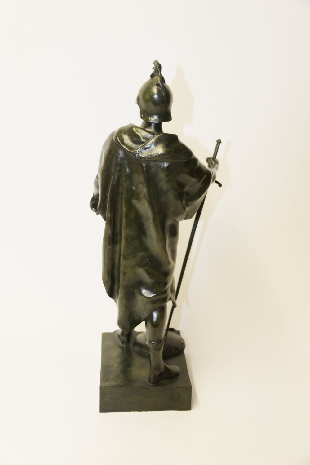 A late 19th-century patinated dark bronze sculpture depicting a Roman warrior with a sword resting against a shield on a rectangular base. View X