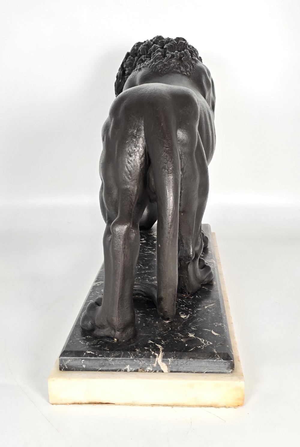 A dark patinated bronze sculpture of a lion resting its paw on a sphere, mounted on a two-tier marble plinth. View IX