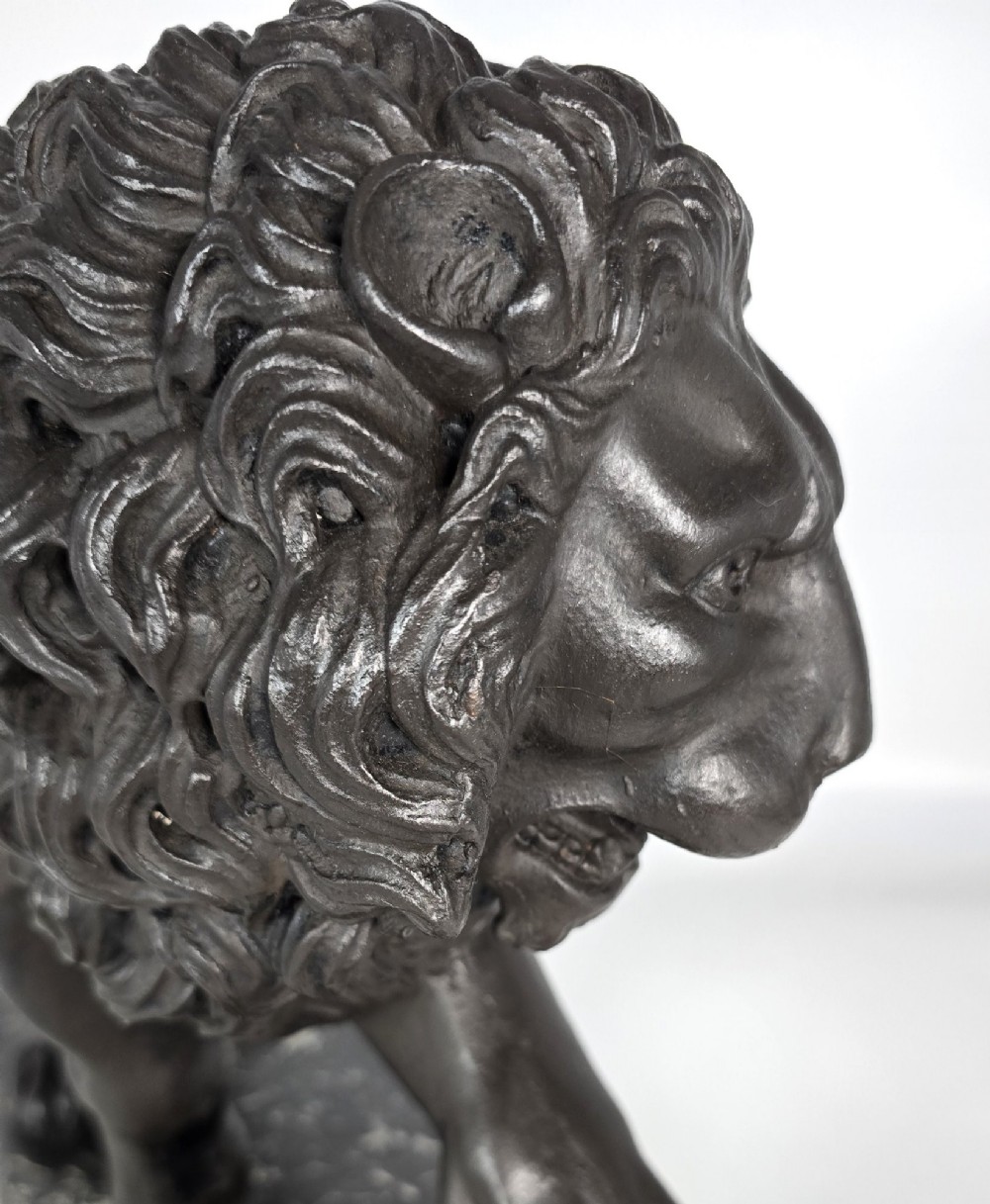 A dark patinated bronze sculpture of a lion resting its paw on a sphere, mounted on a two-tier marble plinth. View XI