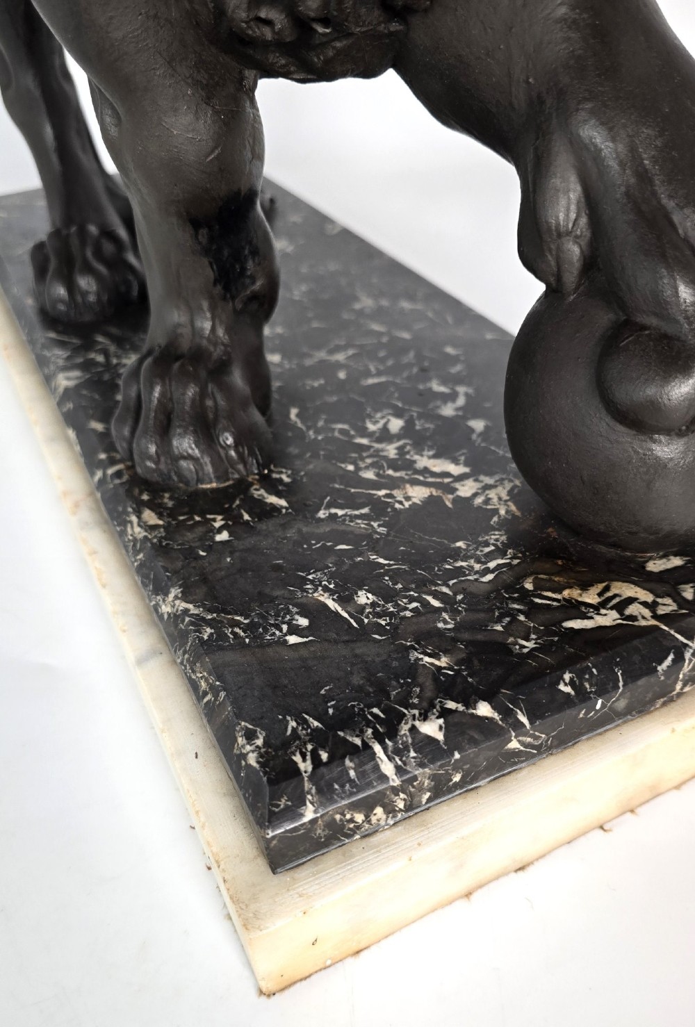 A dark patinated bronze sculpture of a lion resting its paw on a sphere, mounted on a two-tier marble plinth. View XIII