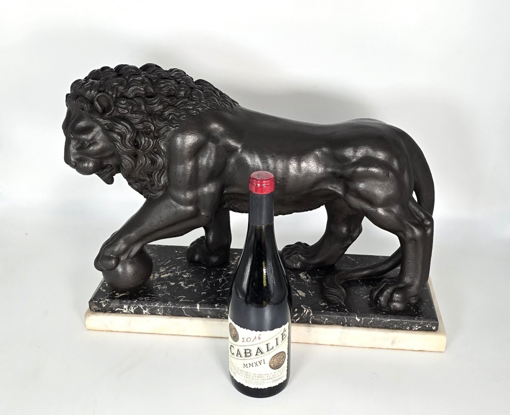 A dark patinated bronze sculpture of a lion resting its paw on a sphere, mounted on a two-tier marble plinth. View XIV