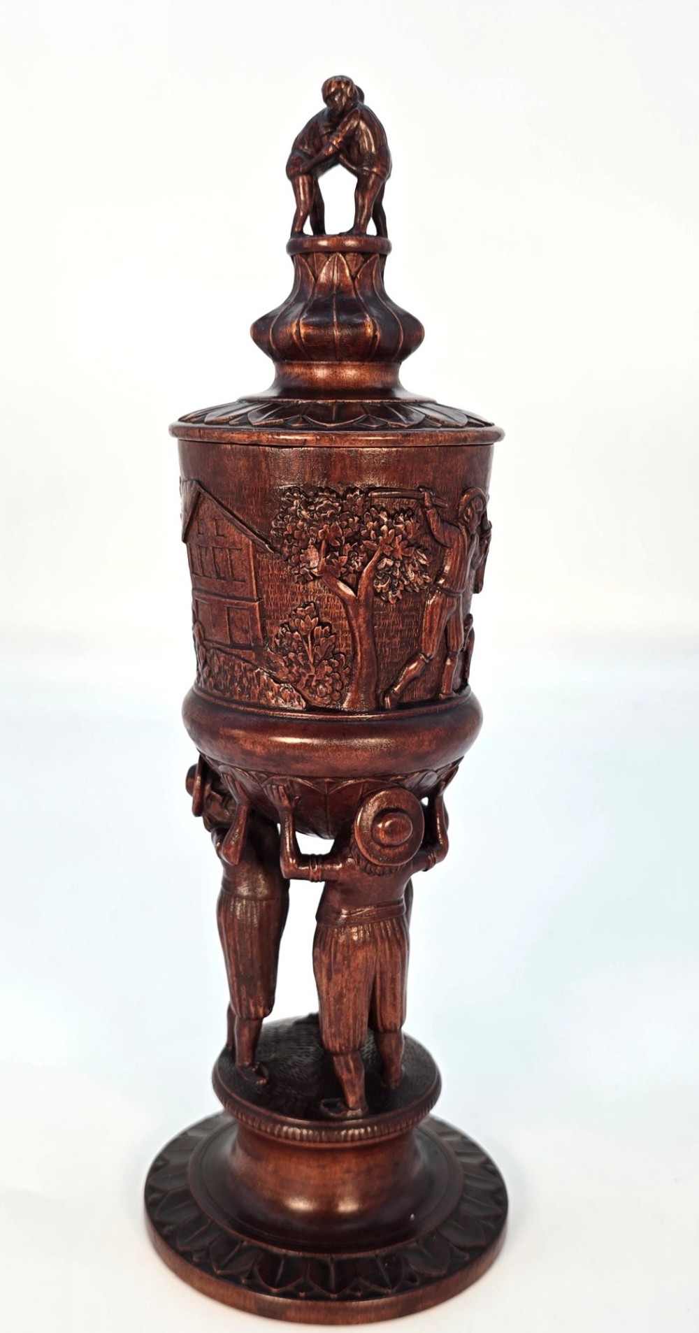 A tall hand-carved dark walnut lidded chalice featuring a stem sculpted as human figures, a relief carving of cattle around the vessel, and a finial with carved figures. View III
