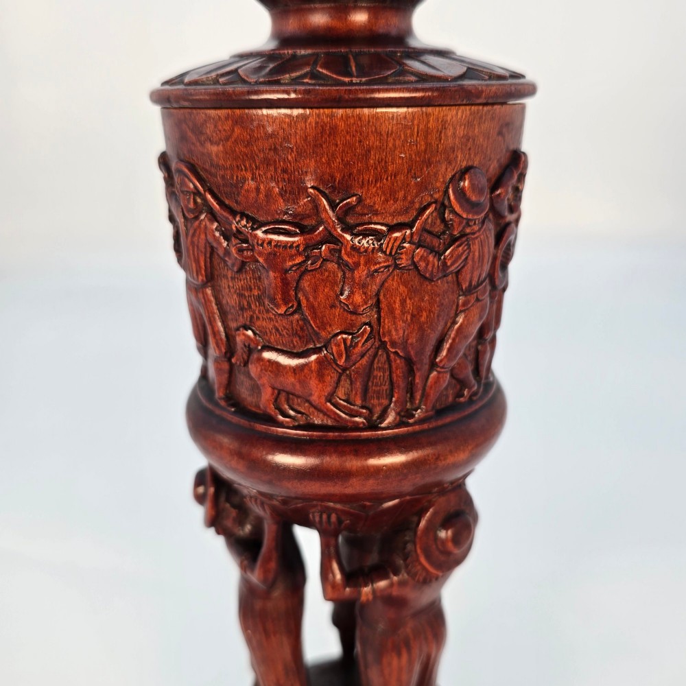 A tall hand-carved dark walnut lidded chalice featuring a stem sculpted as human figures, a relief carving of cattle around the vessel, and a finial with carved figures. View VII