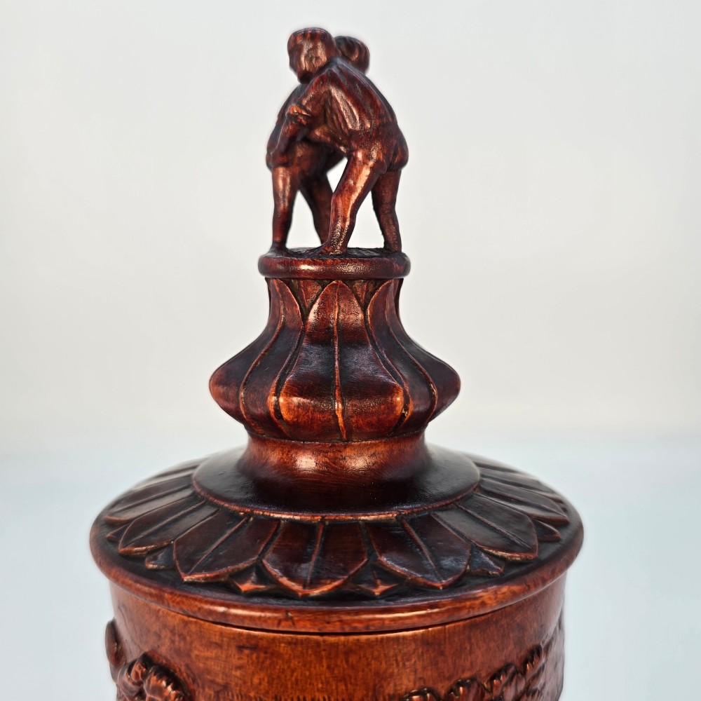 A tall hand-carved dark walnut lidded chalice featuring a stem sculpted as human figures, a relief carving of cattle around the vessel, and a finial with carved figures. View XII
